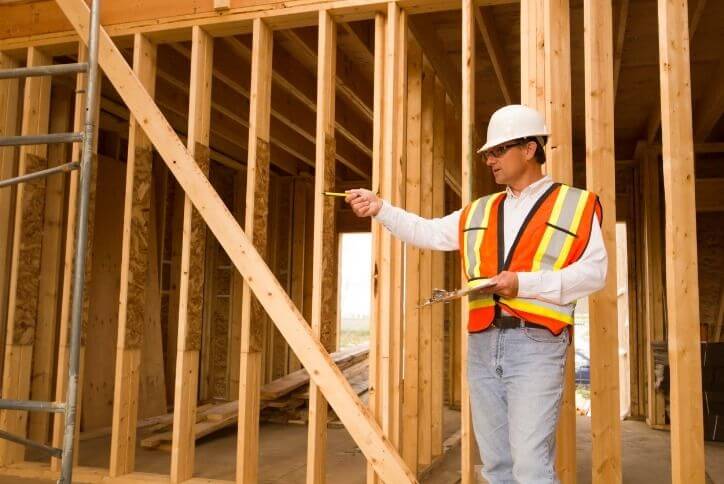 Construction worker in front of wooden structure giving orders.