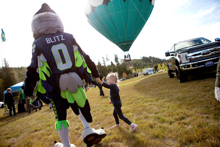 Seattle Seahawks mascot holding little girl's hand.