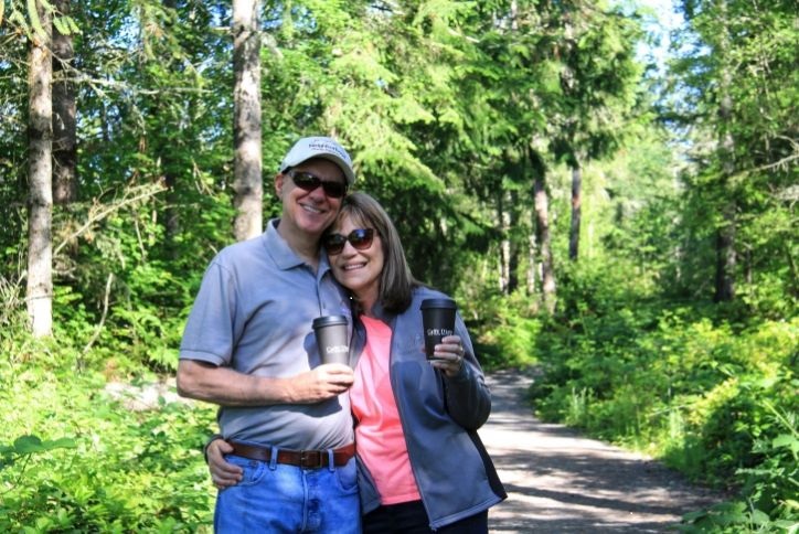 Resident couple holding each other and holding coffee on hike through Tehaleh forest.