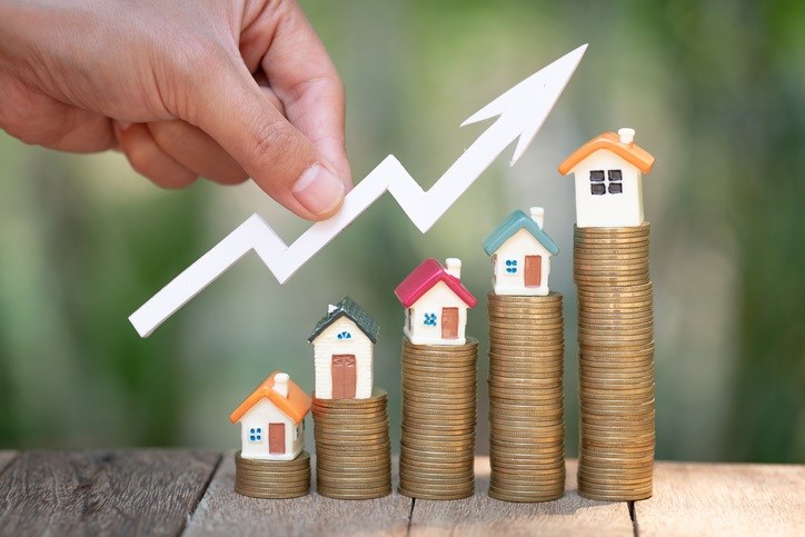 Stacked coins with houses on top depict rising savings.