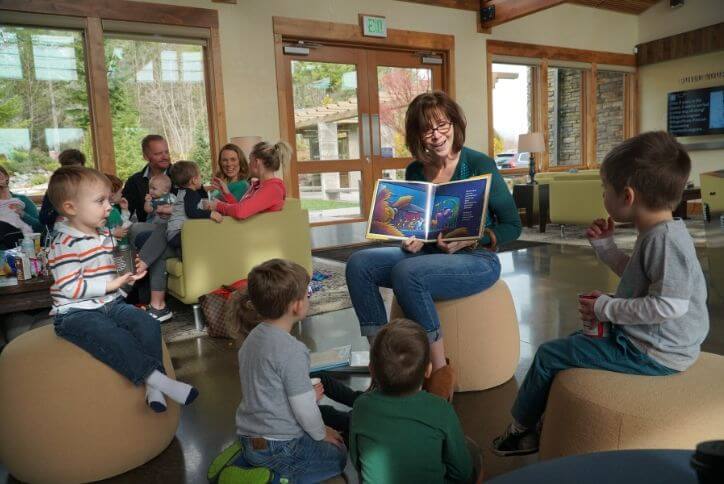 Woman reading from kids book to circle of children at the Post in Tehaleh.