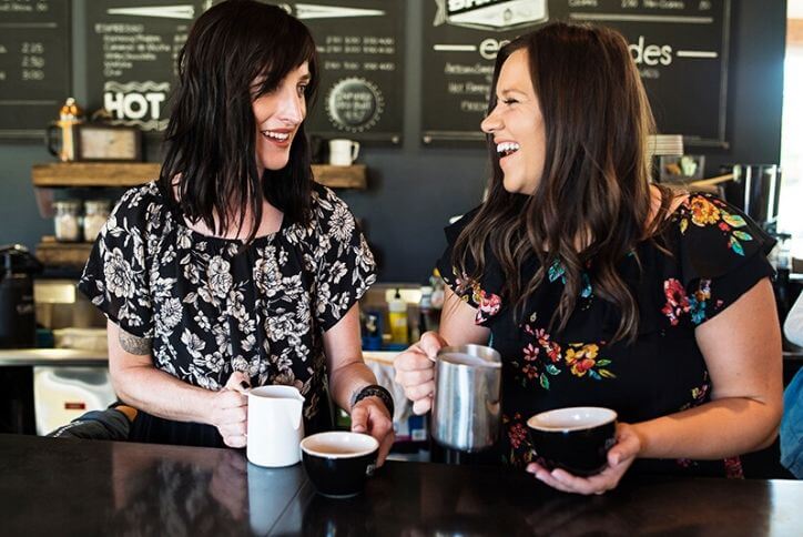 Two women chatting and laughing over coffee at Caffee Darte in Tehaleh.