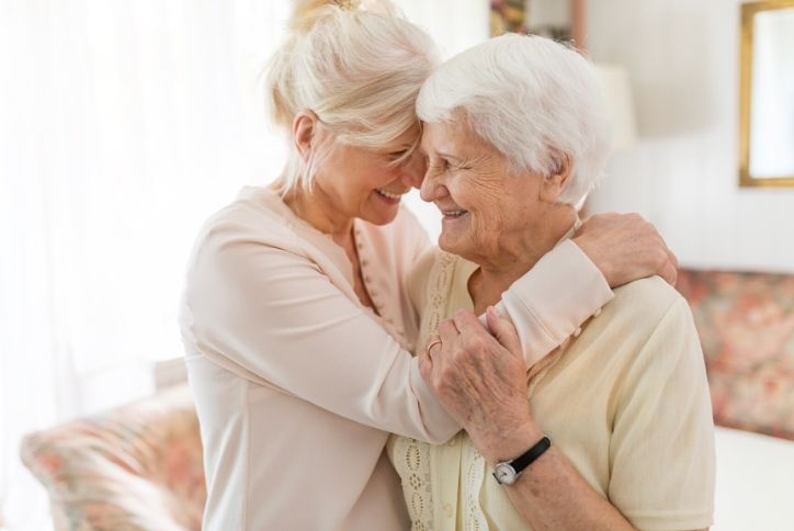 Caregiver giving elderly woman a hug.