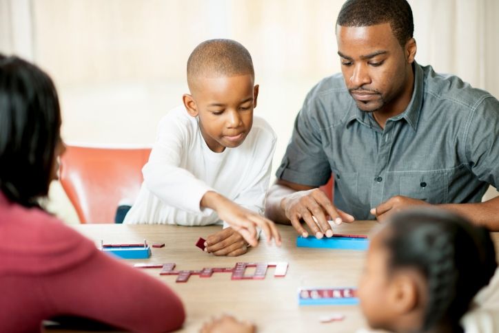 Family playing scrabble on table at home.