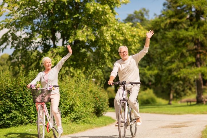 Older couple waiving on their bike ride