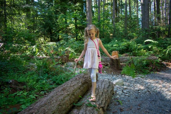 young girl balancing on log in forest near Tehaleh