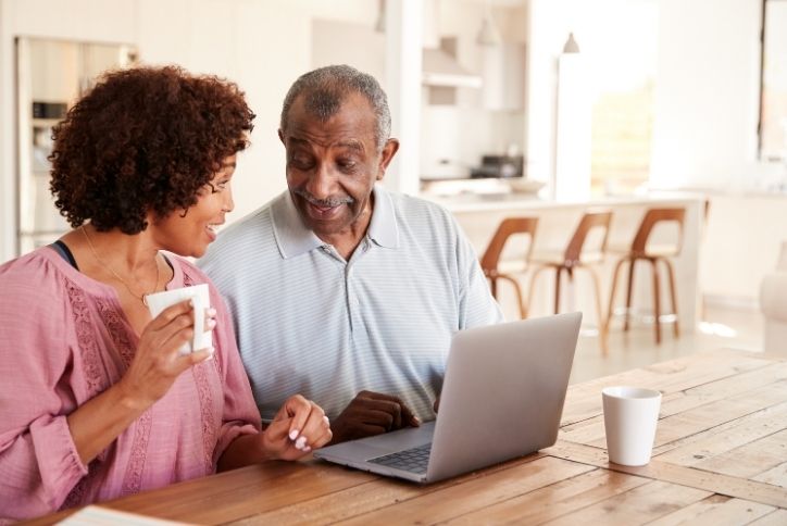 Couple facing each other discussing something from their laptop.