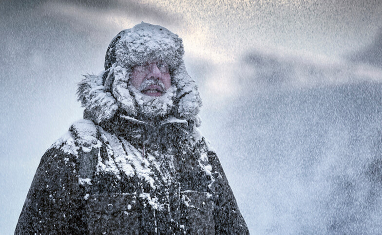 Man in snow storm wearing heavy winter coat.