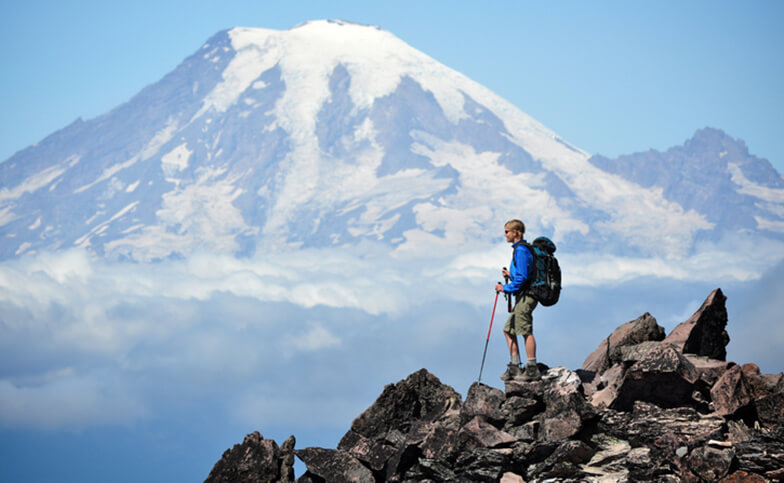 Hiker on top of mountain with view of Mt Rainier.