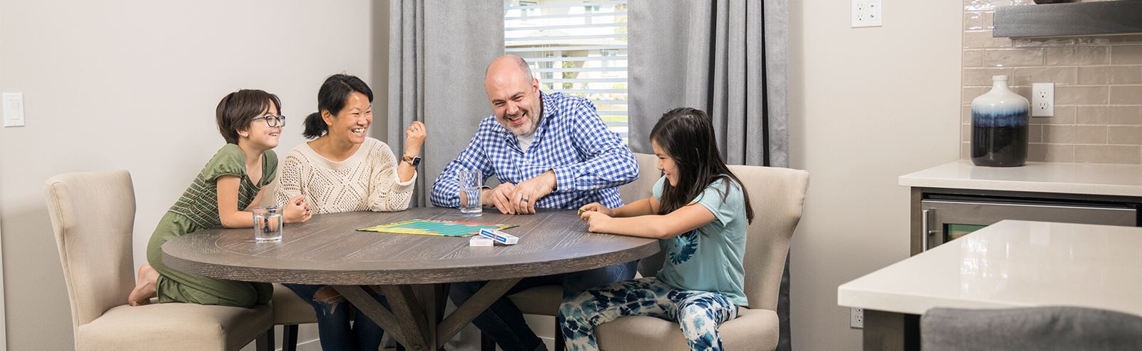 Family of four playing card game at table