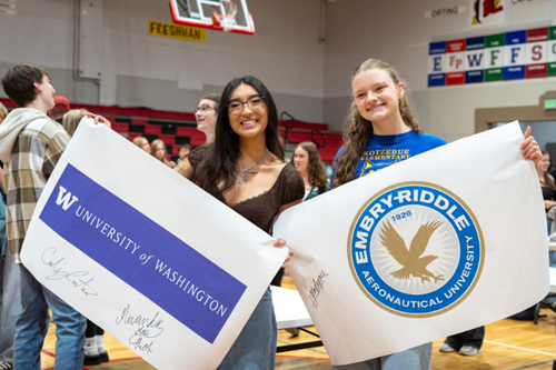 Two Orting high school seniors pose with their college banners.