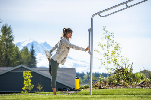 A woman pauses her workout to stretch against one of Reflection Park's few workout structures.