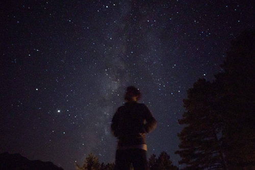 A person stands under a sky full of stars