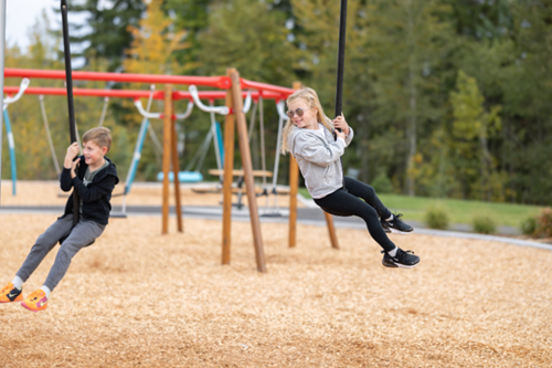 Two children swing on park structure in Skyline Park